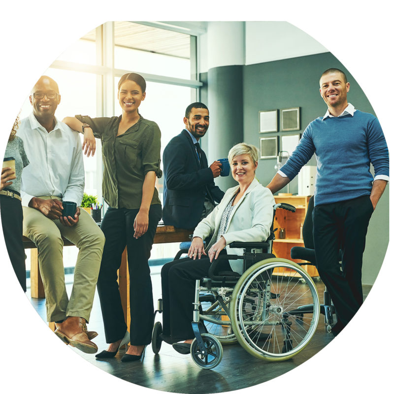 Group of young professionals, one in a wheelchair smiling in an office setting