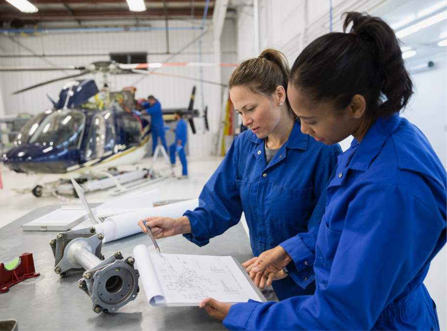 Two women in helicopter hanger discussing plans