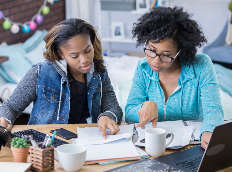 Two women working on computers and reviewing papers