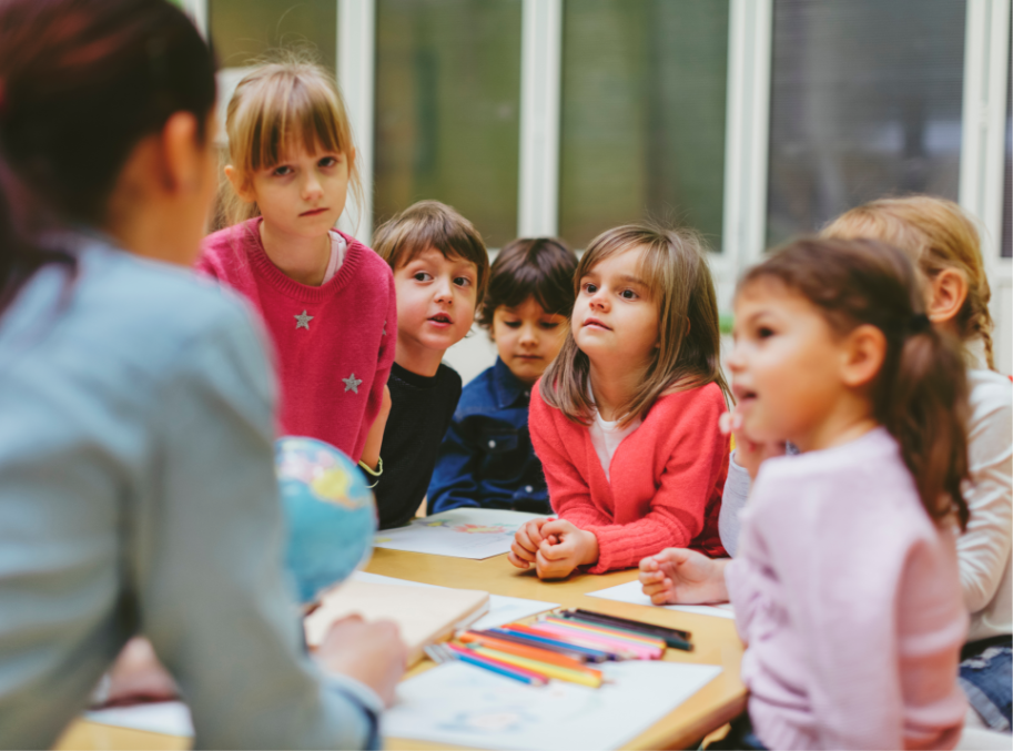 Small children listening closely to teacher in school setting