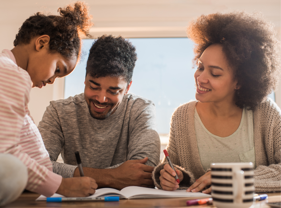 Mom, Dad and young girl writing in notebook at table