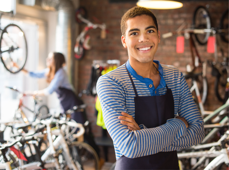 Young man with arms crossed working in a bike store