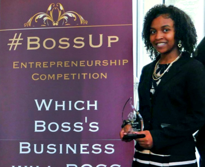 A young girl holding an award at the Boss Up Entrepreneurship Competiton